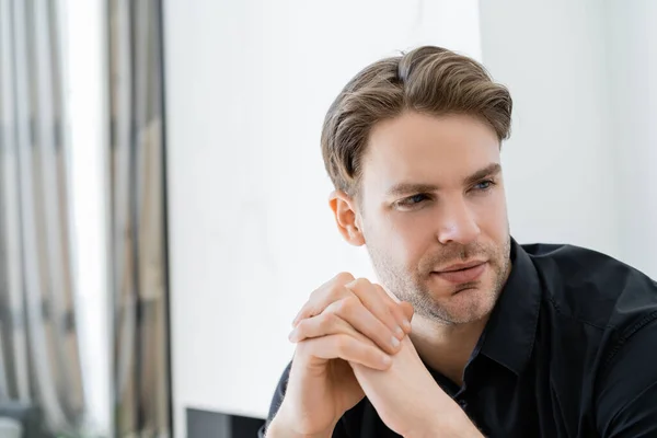 Giovane uomo con le mani serrate guardando lontano a casa — Foto stock