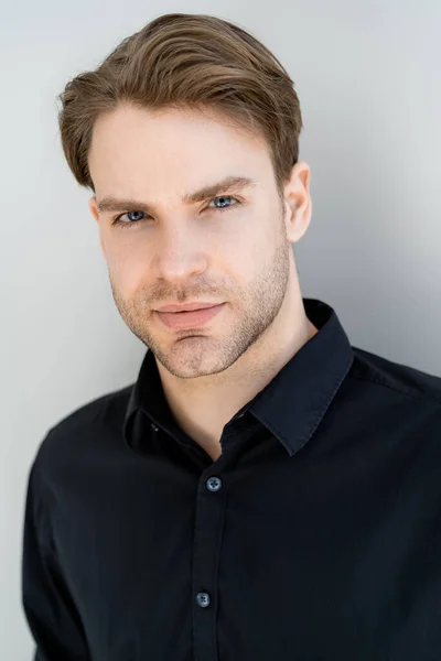 Portrait of young man in black shirt looking at camera isolated on grey — Stock Photo