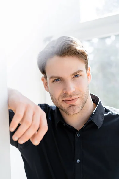 Junger Mann im schwarzen Hemd blickt in die Kamera auf verschwommenem Hintergrund — Stockfoto