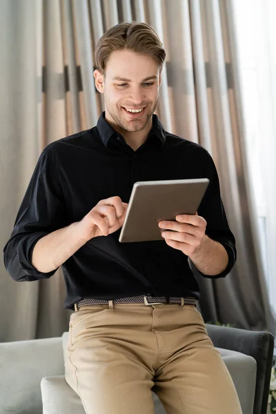 Homem feliz e elegante em camisa preta usando tablet digital em casa — Fotografia de Stock