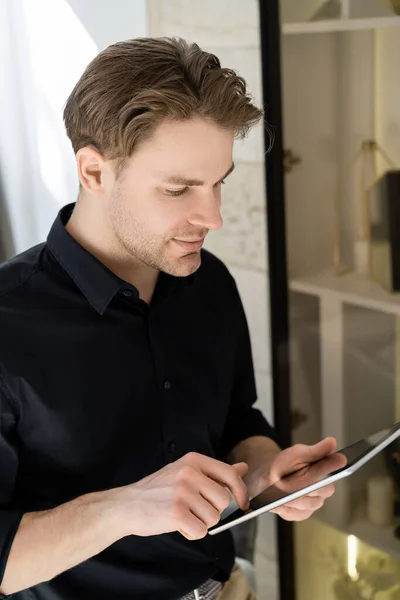 Junger Mann im schwarzen T-Shirt mit digitalem Tablet zu Hause — Stockfoto