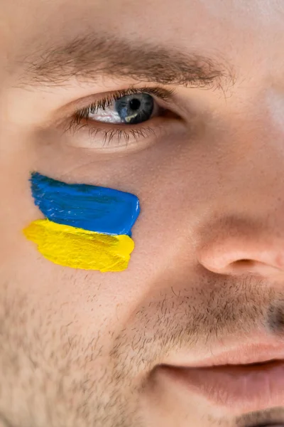 Vista de cerca de la bandera ucraniana pintada en la cara del joven patriota - foto de stock