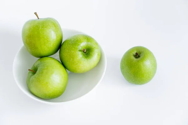 Top view of green and organic apples in bowl on white — стоковое фото