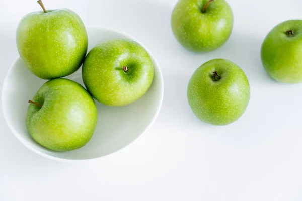 Vista superior de manzanas verdes en tazón sobre blanco - foto de stock