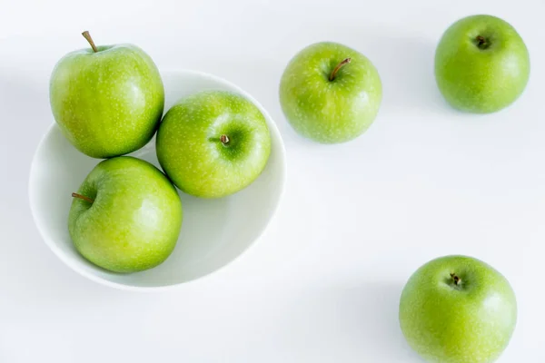 Vista superior de manzanas verdes y jugosas en tazón sobre blanco - foto de stock