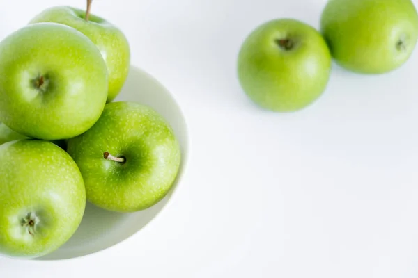 Top view of bowl with green and ripe apples on white — стоковое фото