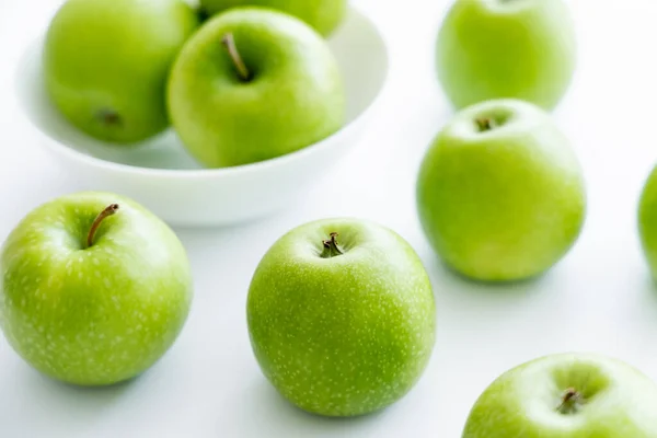 Green and ripe apples near bowl on white — Stock Photo