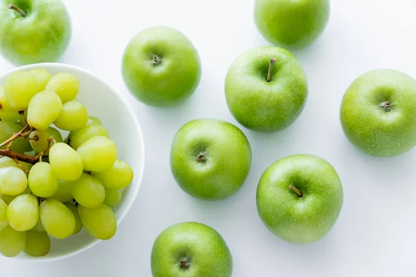 Vista dall'alto di mele verdi e mature vicino a chicchi d'uva in boccia su bianco — Foto stock