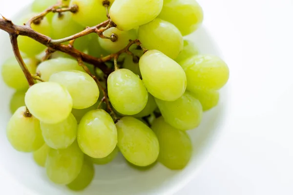 Close up view of fresh grapes in bowl on white - foto de stock