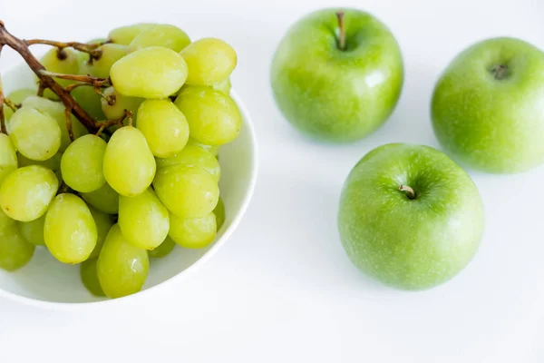 Top view of grapes in bowl near apples on white - foto de stock