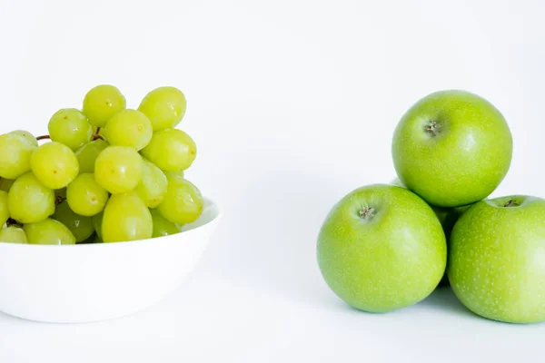 Green grapes in bowl near apples on white — Stock Photo