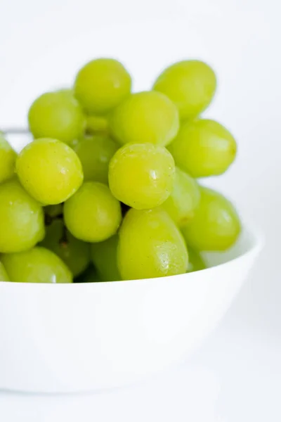 Close up view of sweet green grapes in bowl on white — Stock Photo