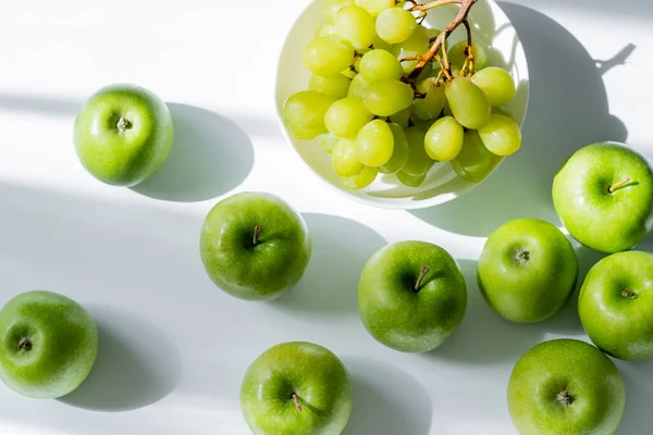 Top view of bowl with sweet grapes and apples on white — Stock Photo