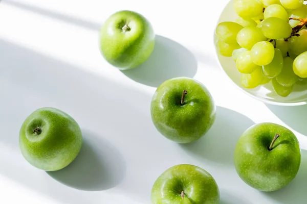 Top view of bowl with sweet grapes and ripe apples on white — Foto stock