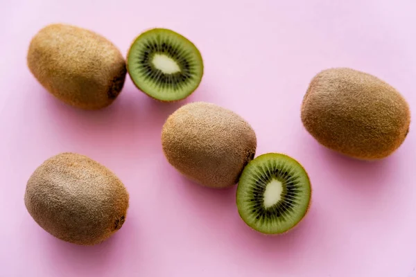 Top view of sweet whole and cut kiwi on pink - foto de stock