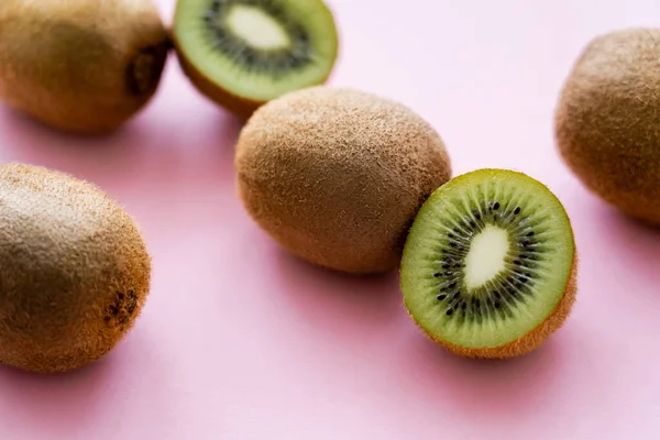 Close up view of sweet whole and cut kiwi on pink — Stock Photo