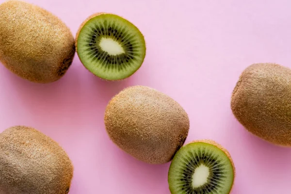 Draufsicht auf Tasse und ganze Kiwi-Früchte auf rosa — Stockfoto