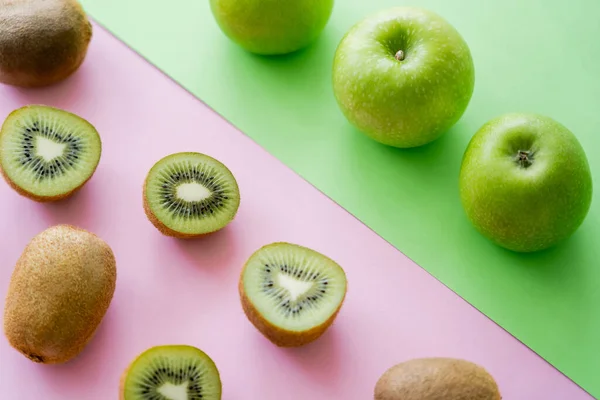 High angle view of rows with apples and kiwi fruits on green and pink - foto de stock