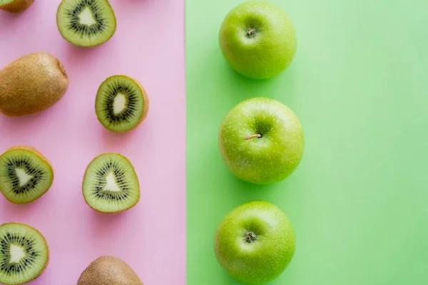 Top view of rows with apples and kiwi fruits on green and pink — стоковое фото
