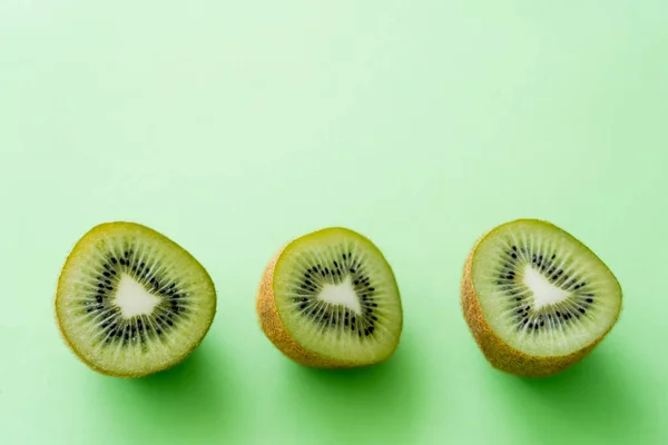 Top view of kiwi fruit halves on green — Stock Photo