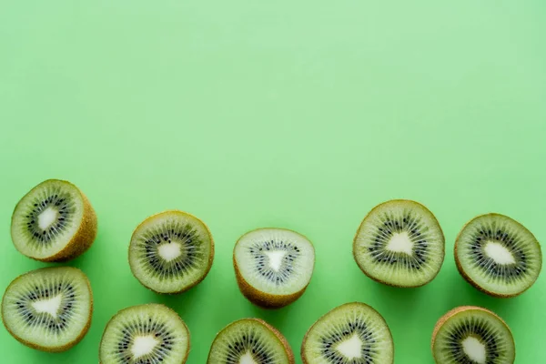 Puesta plana de kiwi fresco mitades de fruta en verde - foto de stock