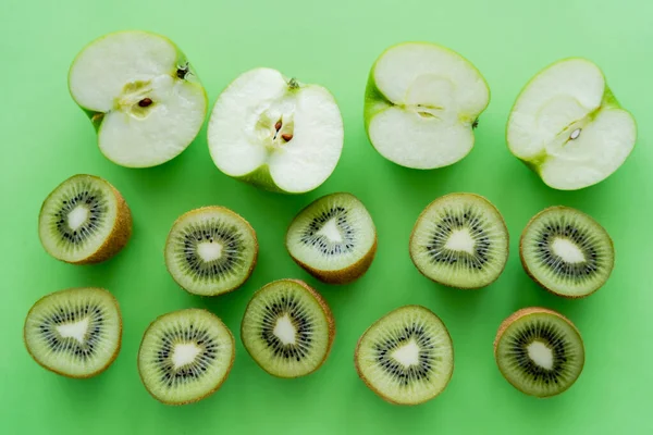 Flat lay of apples and kiwi fruits halves on green — Fotografia de Stock