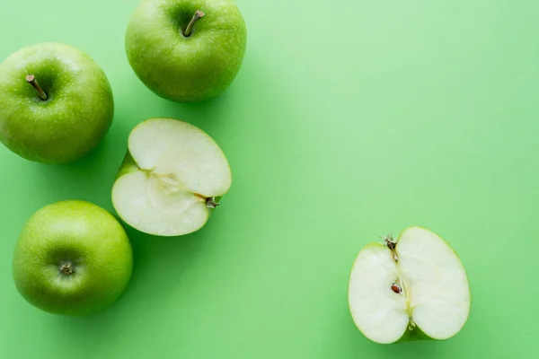 Плоская выкладка целых и нарезанных сочными яблоками на зелень — стоковое фото