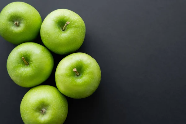 Vista superior de manzanas enteras y verdes en negro - foto de stock