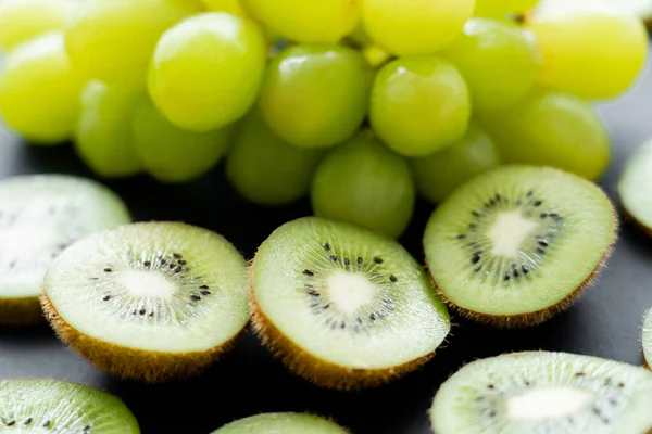 Close up view of green grapes and sliced fresh kiwi on black — Photo de stock