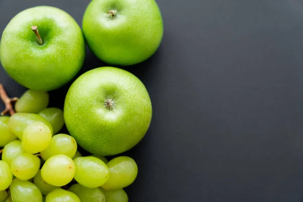 Vista dall'alto di mele saporite e uva verde su nero — Foto stock