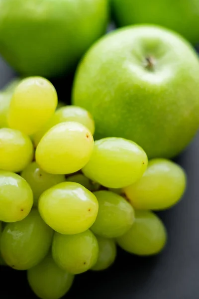 Close up view of tasty apples and green grapes on black — Photo de stock