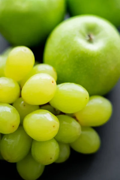 Close up view of tasty apples and green grapes on black — Fotografia de Stock