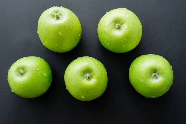 Flache Lage grüner und frischer Äpfel mit Wassertropfen auf schwarz — Stockfoto