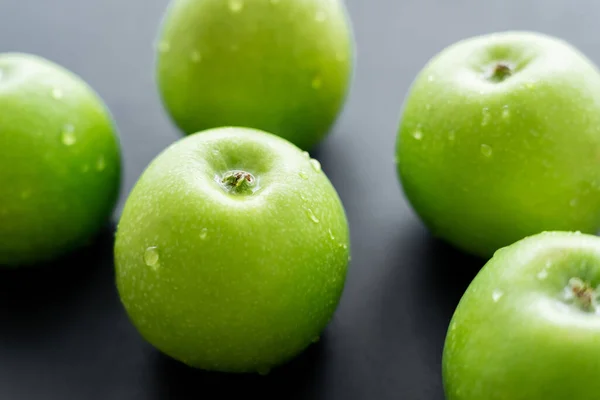 Close up view of water drops on green and ripe apples on black — стоковое фото