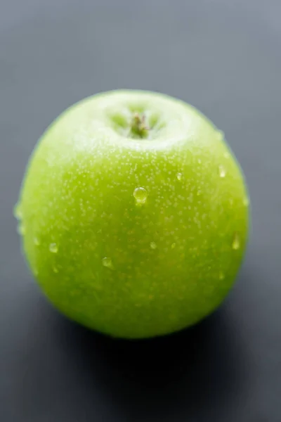 Close up view of green and fresh apple with water drops on black — Stock Photo