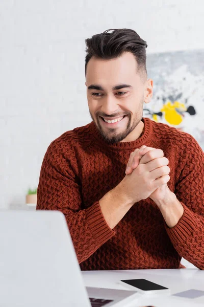 Cheerful bookmaker with clenched hands looking at laptop — стоковое фото