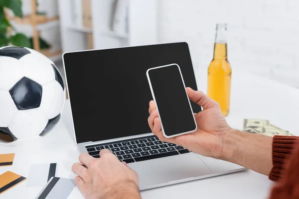 Обрізаний вид букмекерської контори з мобільним телефоном біля ноутбука, футбольного м'яча та кредитних карток — стокове фото