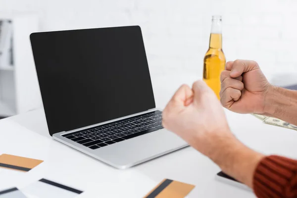 Partial view of gambler holding clenched fists for luck near laptop with blank screen — Photo de stock