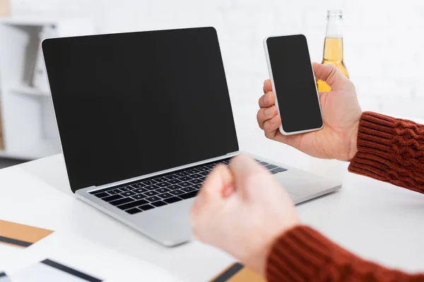 Обрізаний вид букмекера, що тримає згорнутий кулак удачі біля ноутбука та смартфона з порожнім екраном — стокове фото