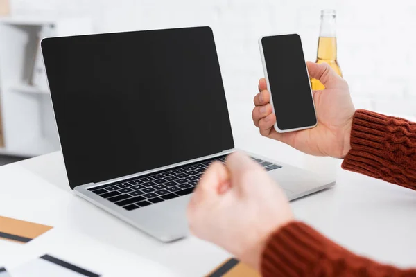 Cropped view of bookmaker holding clenched fist for luck near laptop and smartphone with blank screen — Photo de stock