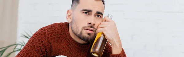 Depressed bookmaker with bottle of beer looking away at home, banner — Foto stock