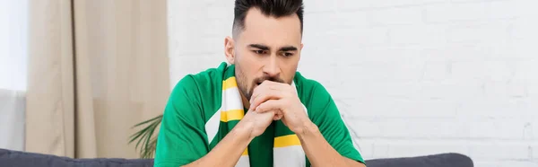 Frustrated sports fan in striped scarf holding hands near face, banner — Stock Photo