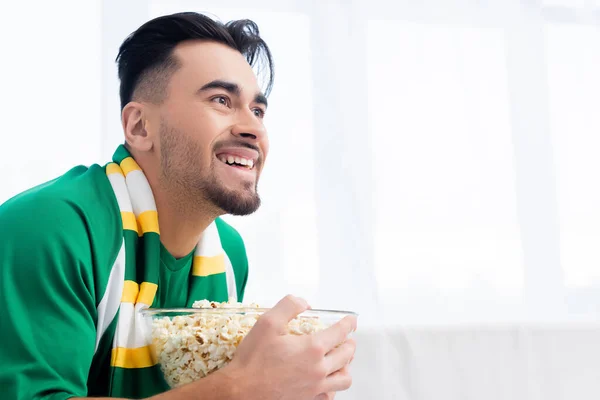 Joyful sports fan with popcorn watching championship at home — Stock Photo