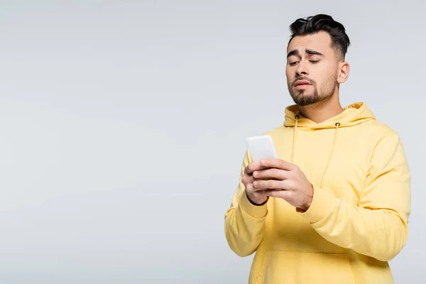 Tense bookmaker looking at mobile phone isolated on grey — стоковое фото