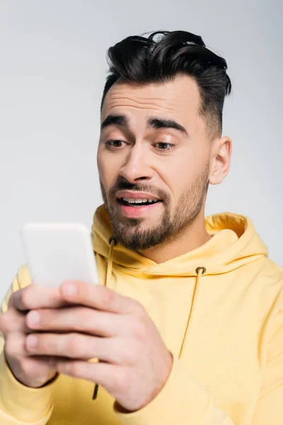 Jugador preocupado mirando el teléfono móvil borroso aislado en gris - foto de stock