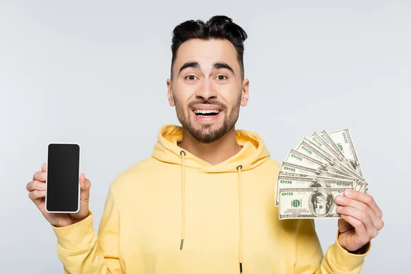 Joyeux bookmaker tenant billets en dollars et smartphone avec écran vierge isolé sur gris — Photo de stock