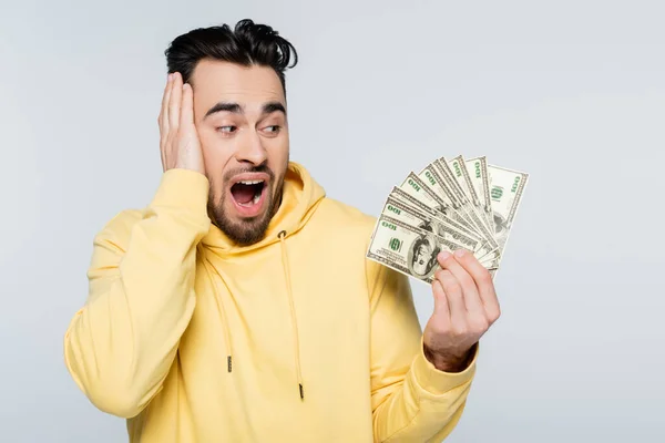 Amazed bookmaker looking at dollar banknotes isolated on grey — Photo de stock