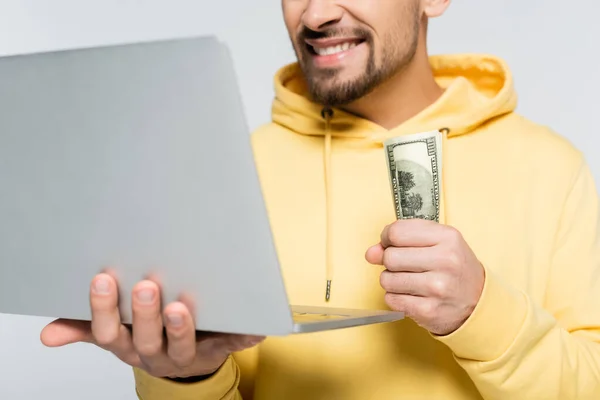 Vista cortada do jogador sorrindo segurando dólares perto laptop isolado em cinza — Fotografia de Stock