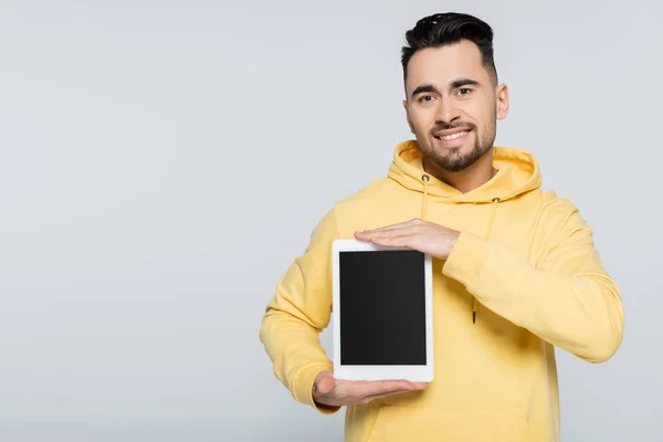 Happy man in yellow hoodie holding digital tablet with blank screen isolated on grey — Stock Photo