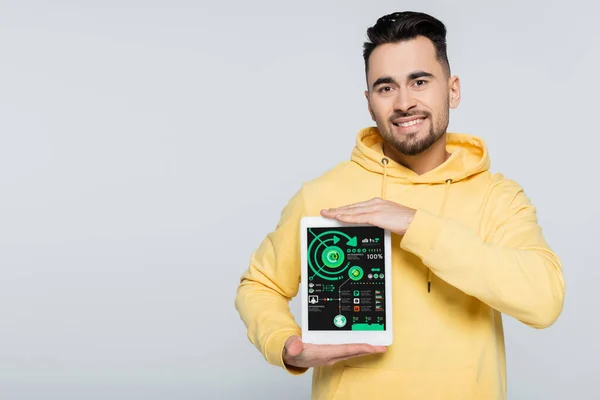 Cheerful man showing digital tablet with infographics isolated on grey — Stock Photo